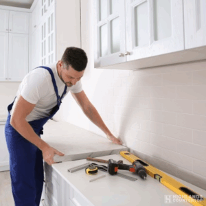 Worker installing a quartz countertop in a modern kitchen, carefully aligning the slab over the cabinetry.